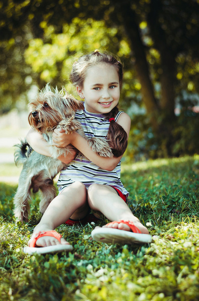Happy little girl playing with dog on the grass - Zdjęcie, obraz