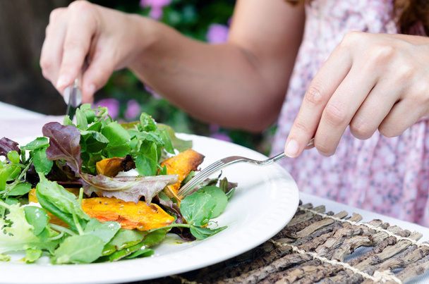 Mains de femme et salade verte pendant un repas
 - Photo, image