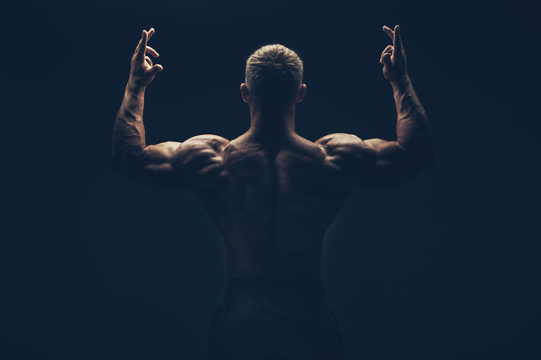 Handsome muscular bodybuilder posing over black background. - Valokuva, kuva