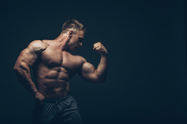 Handsome muscular bodybuilder posing over black background. - Foto, Imagem