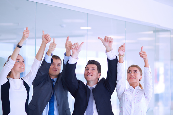 Feliz equipo de negocios mostrando pulgares hacia arriba en la oficina
 - Foto, Imagen