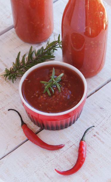 salsa de tomate con chile y botellas en una madera
 - Foto, imagen