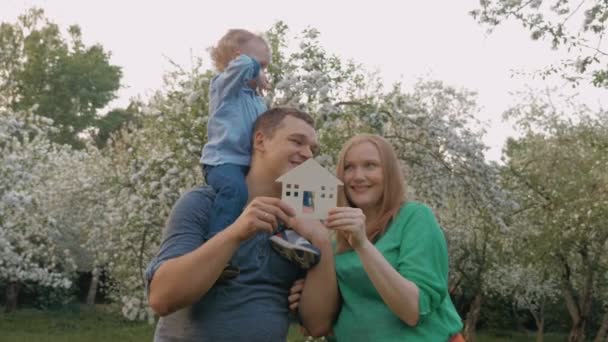 Šťastná rodina s modelem domu jako koncept nemovitostí - Záběry, video
