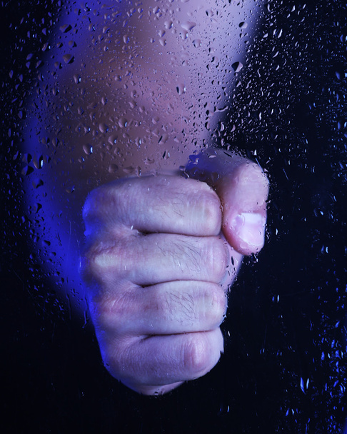 Male hand behind  wet glass, close-up - Foto, afbeelding