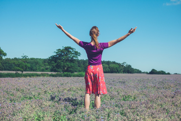 Mujer levantando sus brazos en un campo de flores púrpuras
 - Foto, Imagen