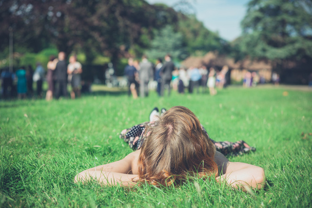 Vrouw ontspannen op gras op feestje - Foto, afbeelding