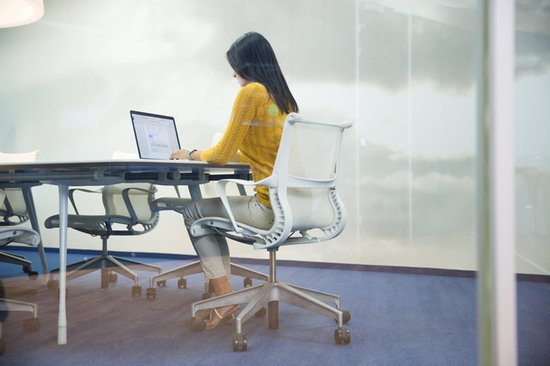 Businesswoman working on laptop in office - Фото, изображение