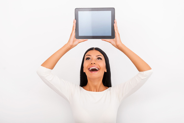 woman holding digital tablet above her head - Foto, afbeelding