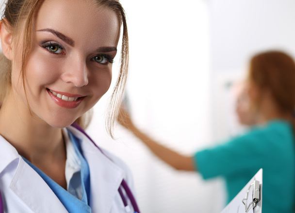 Όμορφη χαμογελαστά γυναικεία ιατρική γιατρός ψάχνει κεκλεισμένων των θυρών - Φωτογραφία, εικόνα
