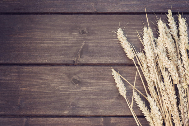 Vintage photo of ears of wheat lying on a wooden desk - Fotografie, Obrázek