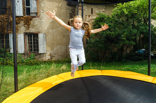 Cute preschooler girl jumping on trampoline - Zdjęcie, obraz