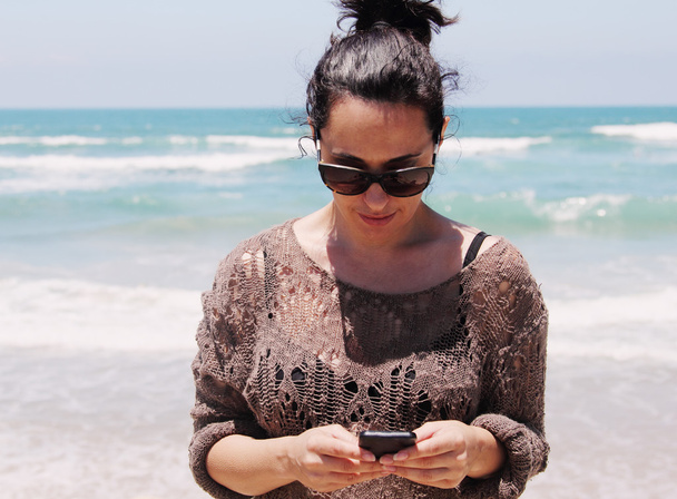 woman with cellphone on the beach - Фото, зображення