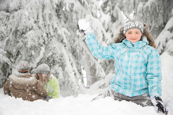 Chica con bola de nieve en el bosque cubierto de nieve
 - Foto, imagen