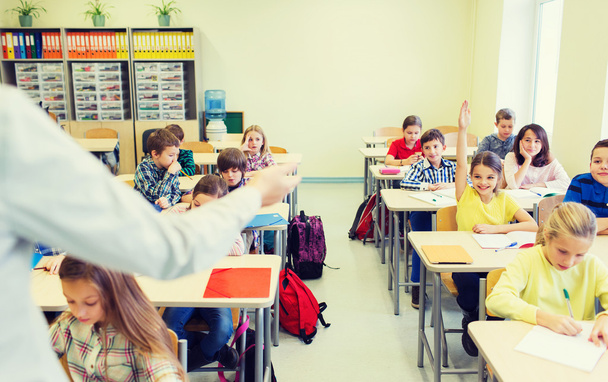 group of school kids raising hands in classroom - Photo, image