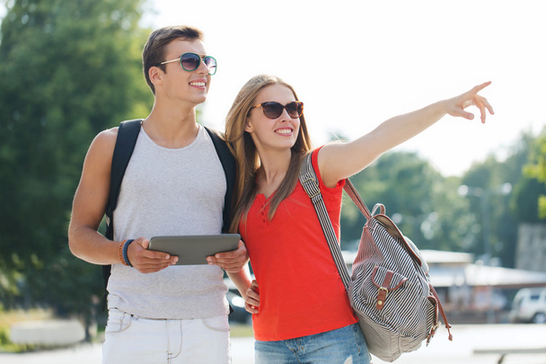 smiling couple with tablet pc and backpack in city - Photo, Image