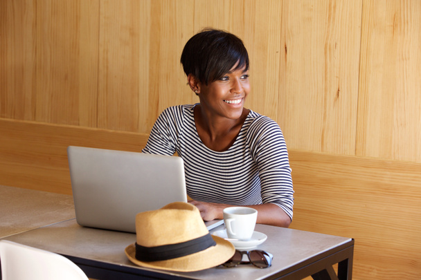 junge schwarze Frau lächelt und benutzt Laptop - Foto, Bild
