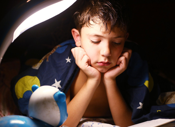 nedospělý hezký kluk četl knihu s lampou před spaním - Fotografie, Obrázek