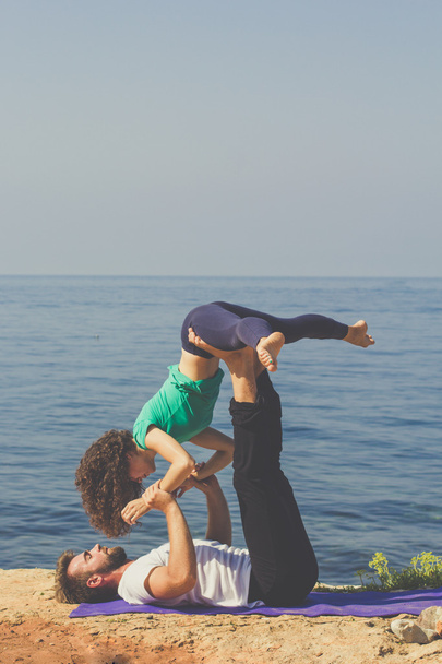 Sportive couple are practicing yoga on the beach - Фото, зображення