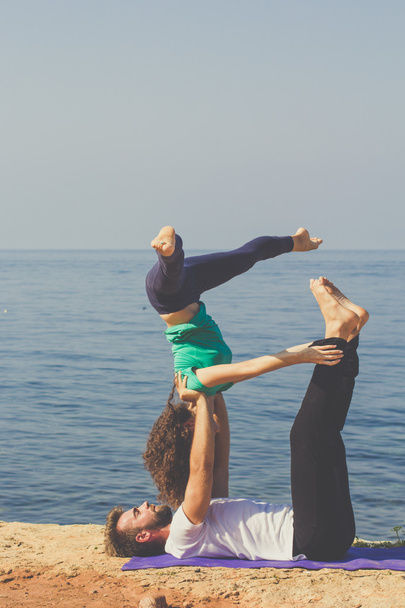 Esportivo jovem casal estão praticando ioga na praia
 - Foto, Imagem
