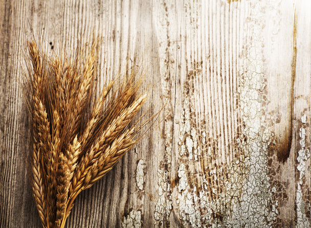 Spikelets of wheat on old wooden table - Фото, зображення