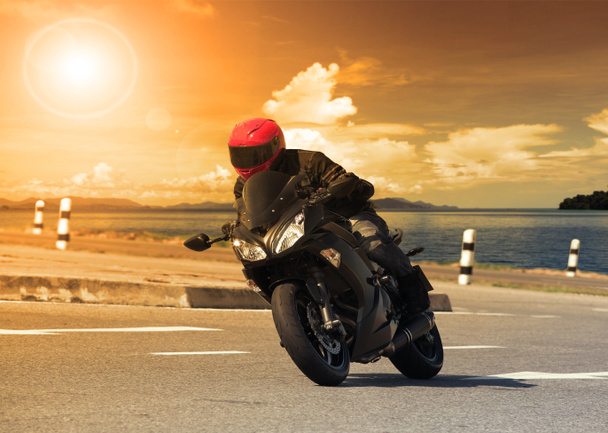 Молодой человек едет на большом мотоцикле против резкого изгиба осины
 - Фото, изображение