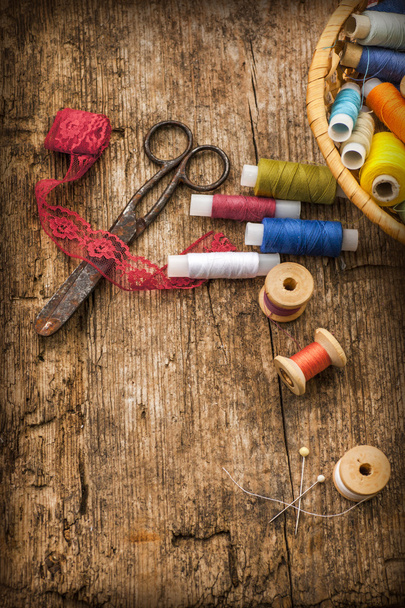 bobbins, needles, scissors on wooden table - Фото, изображение