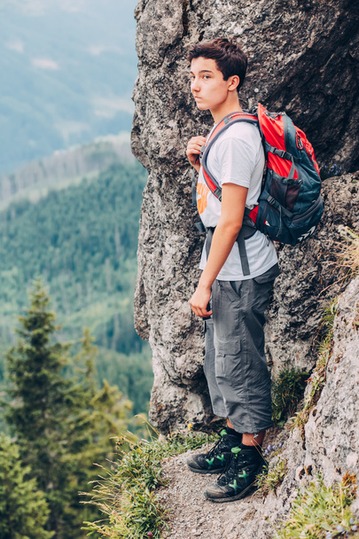 Boy standing on the rocks in the mountains - Fotoğraf, Görsel