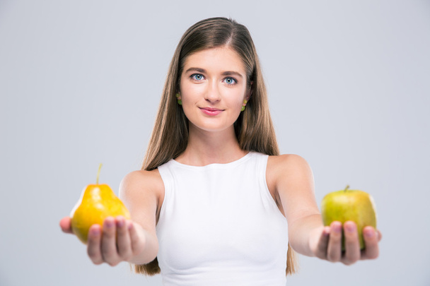 Female teenager holding apple and pear - 写真・画像