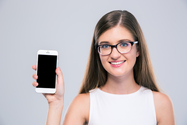 Female teenager in glasses showing blank smartphone screen - Valokuva, kuva