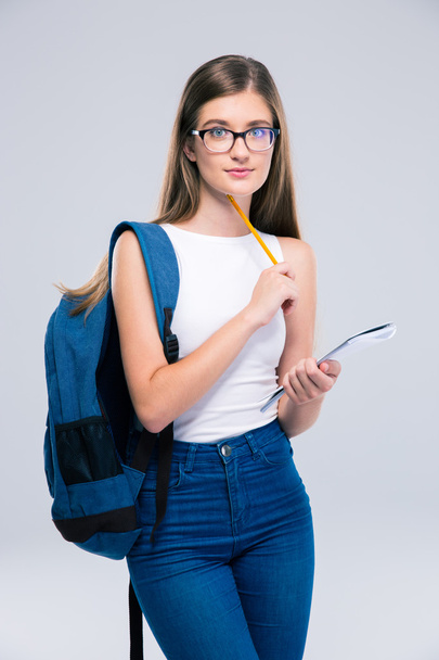 Teenager with backpack holding pencil and notebook - Fotó, kép