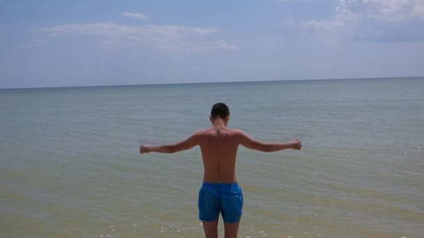 Ένας νεαρός άνδρας στέκεται στην παραλία - Πλάνα, βίντεο