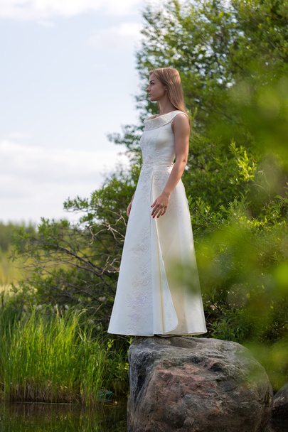 κορίτσι σε λευκό φόρεμα με τη λίμνη στο πράσινο ενάντια στον ουρανό - Φωτογραφία, εικόνα