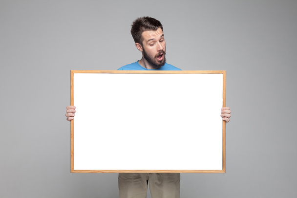 The surprised man showing empty white billboard or banner  - Foto, afbeelding