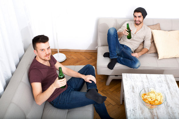 Two Friends with beer and chips in the living room - Photo, image