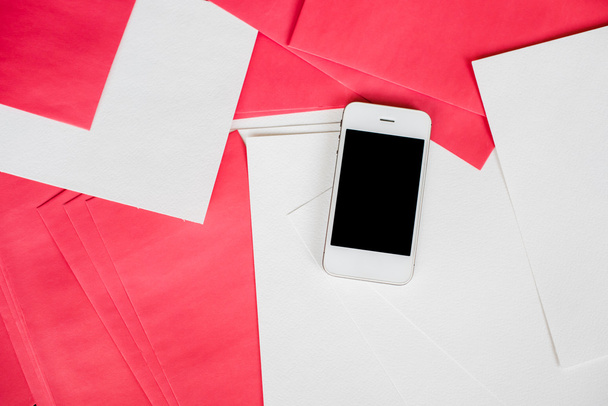 Смартфон с белыми и красными бумажными листами
 - Фото, изображение