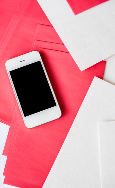 Smartphone con hojas de papel blanco y rojo
 - Foto, Imagen