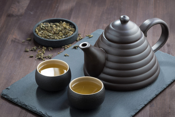 свежезаваренный зеленый чай в керамической посуде на деревянном столе
 - Фото, изображение