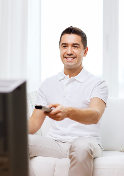 smiling man with remote control watching tv - Foto, imagen