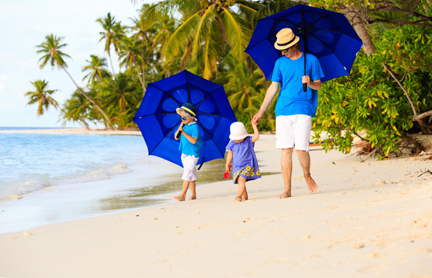 Vater und Kinder am Strand mit Sonnenschirmen zum Verstecken - Foto, Bild