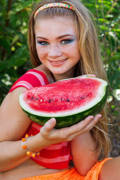 Teen pretty girl is eating watermelon over grass background - Foto, imagen