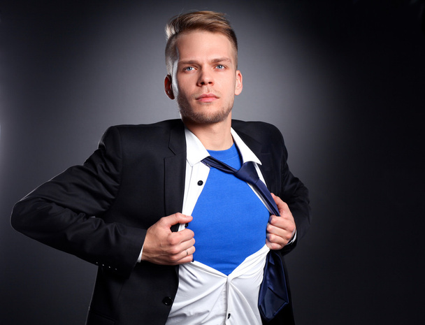 Молодой бизнесмен ведет себя как супергерой и разрывает рубашку, изолированный на сером фоне
 - Фото, изображение