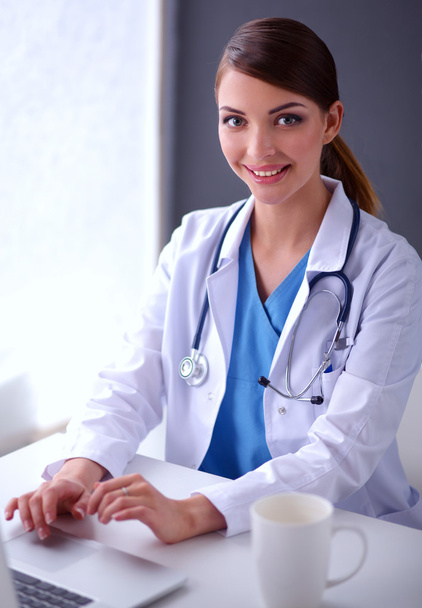 Medico donna che lavora seduto su sfondo grigio - Foto, immagini