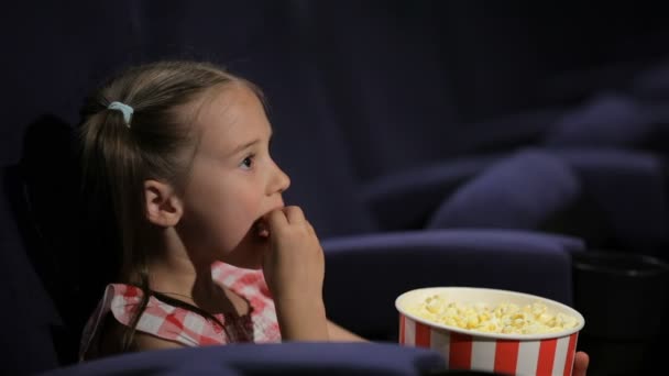 Beautiful little girl waching movie in the cinema - Záběry, video