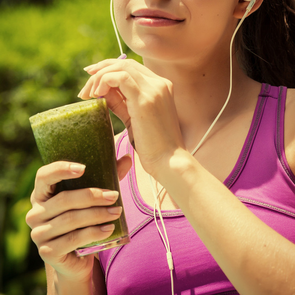 Athletic girl holding a green smoothie - Foto, afbeelding