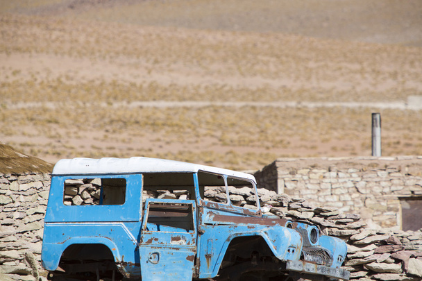 Quebrado 4x4 estacionado na frente da casa de pedras rurais, Bolívia
 - Foto, Imagem