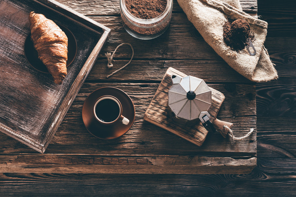 Koffiekopje en ingrediënten op oude houten tafel in avond venster - Foto, afbeelding