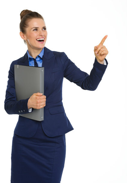 Happy businesswoman holding file, pointing upwards, and smiling - 写真・画像