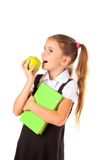 Beautiful little girl in school uniform, book and apple isolated on white - Фото, изображение