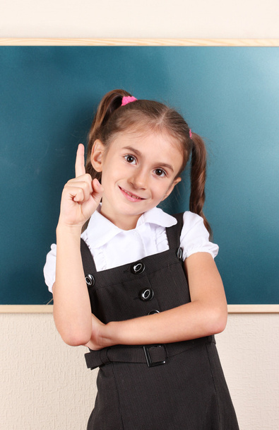Beautiful little girl standing near blackboard in the classroom - Fotoğraf, Görsel
