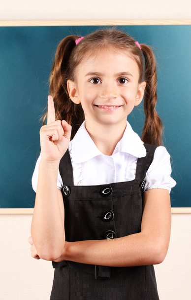Beautiful little girl standing near blackboard in the classroom - Фото, зображення